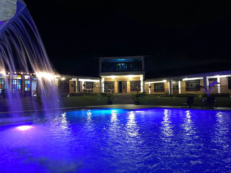 Cascada de la piscina iluminada de noche, con la casa al fondo