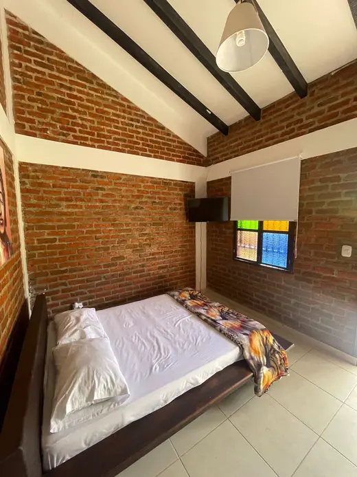 Habitación con cama de madera y vitral de colores